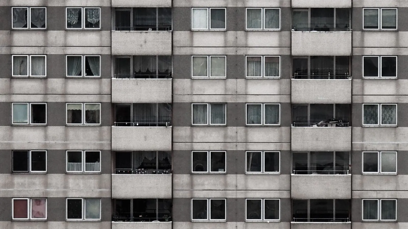 The grey façade of a high-rise apartment block in Berlin, row upon row of identical windows and balconies — file stock photo, not a building named in the coalition plan, no identifiable people