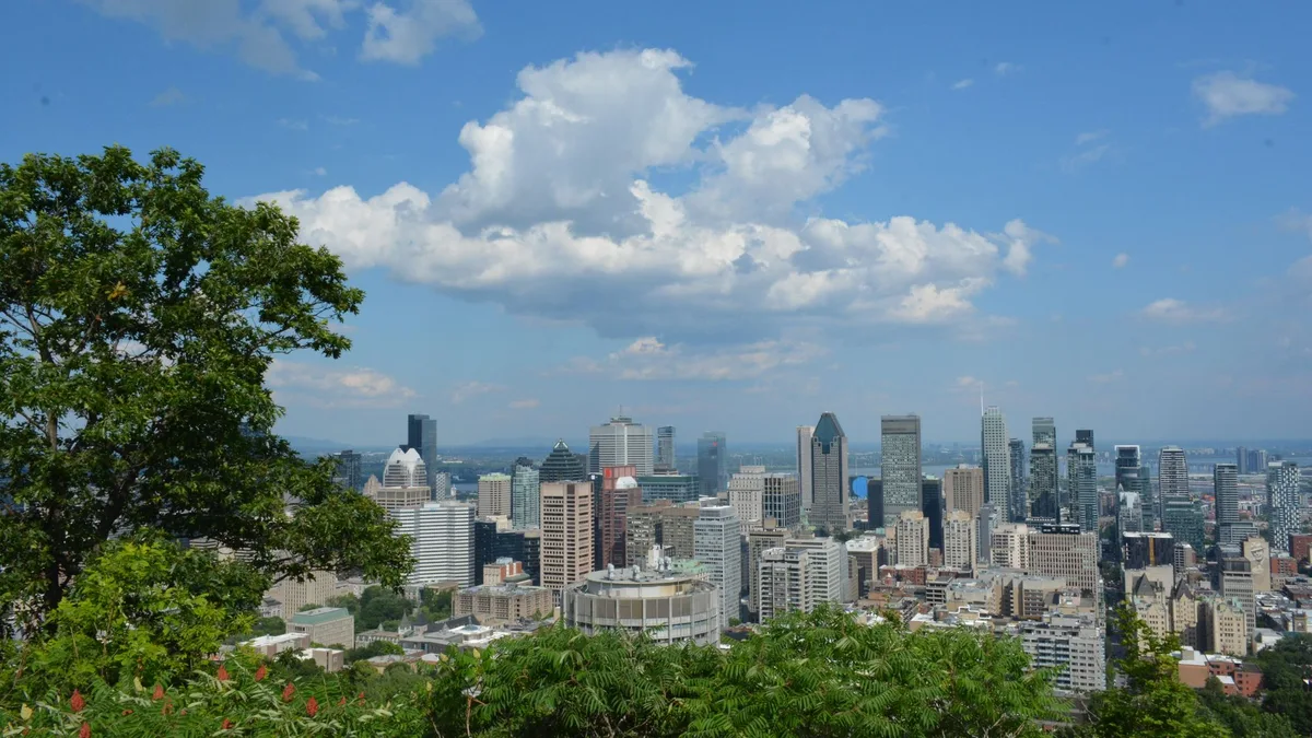 Downtown Montreal's skyline seen from Mount Royal on a sunny day, trees in the foreground — file stock photo, Montreal hosts the EU–Canada summit on 29–30 October, no identifiable people
