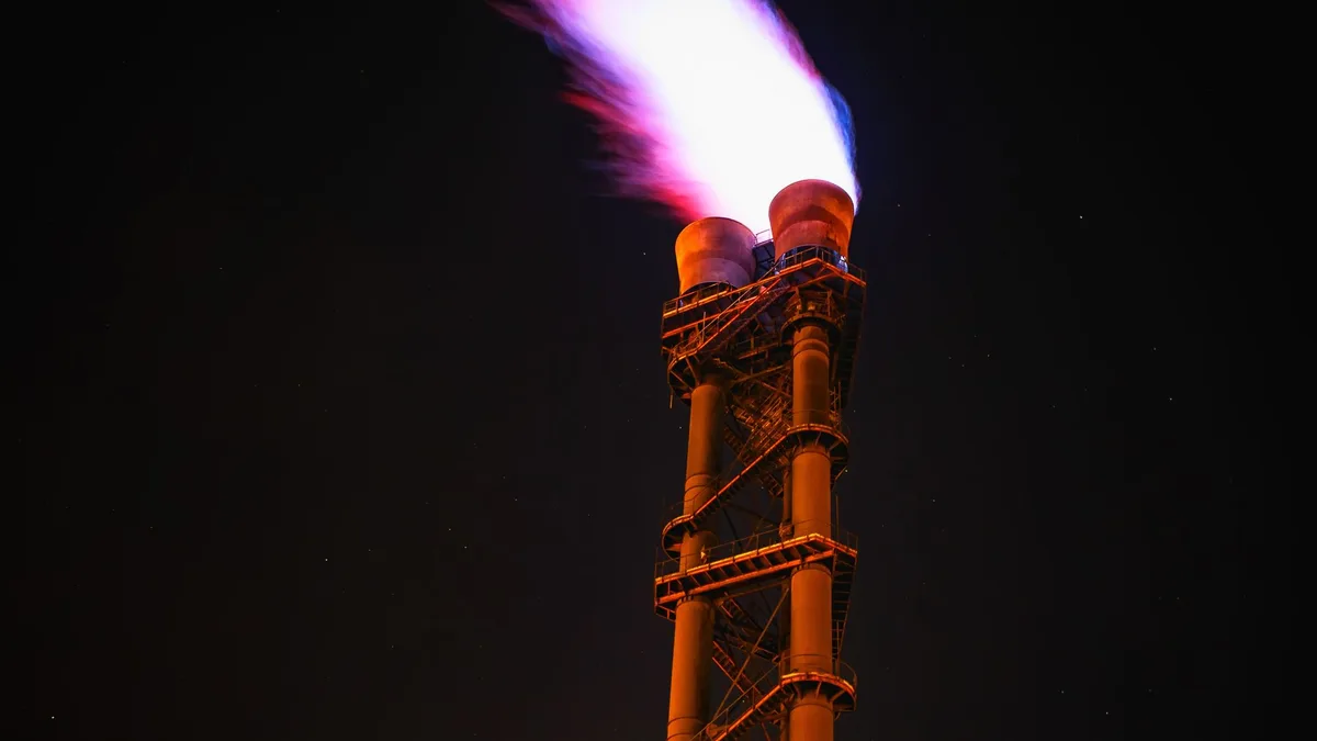 A gas flare burning at the top of an industrial flare stack against a night sky — file stock photo, not a specific EU or exporting-country facility, no people