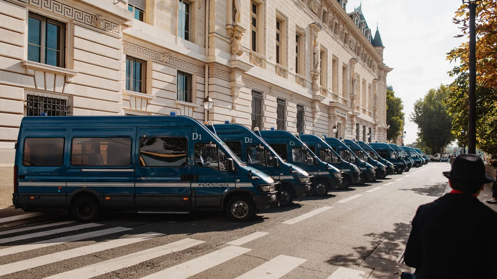 A long line of blue Gendarmerie vans parked beside a historic stone building on a Paris street — file stock photo, not taken during the October 2026 protests, no identifiable people