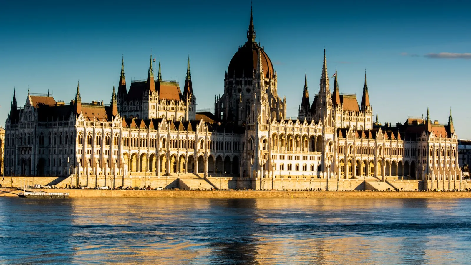 The Hungarian Parliament Building on the Danube in Budapest at golden hour, reflected in the river — file stock photo, not taken at the 2026 commemorations, no identifiable people