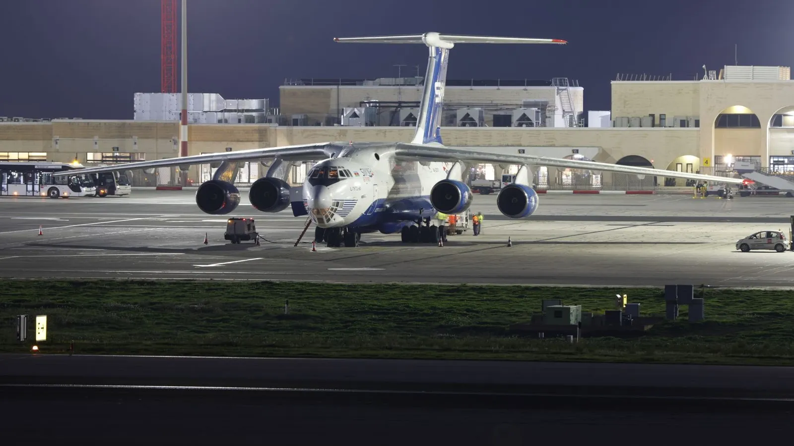 A four-engined cargo jet parked on a floodlit airport apron at night — file stock photo, not Leipzig/Halle Airport and not the Ukrainian aircraft targeted in August; ground staff distant and unidentifiable