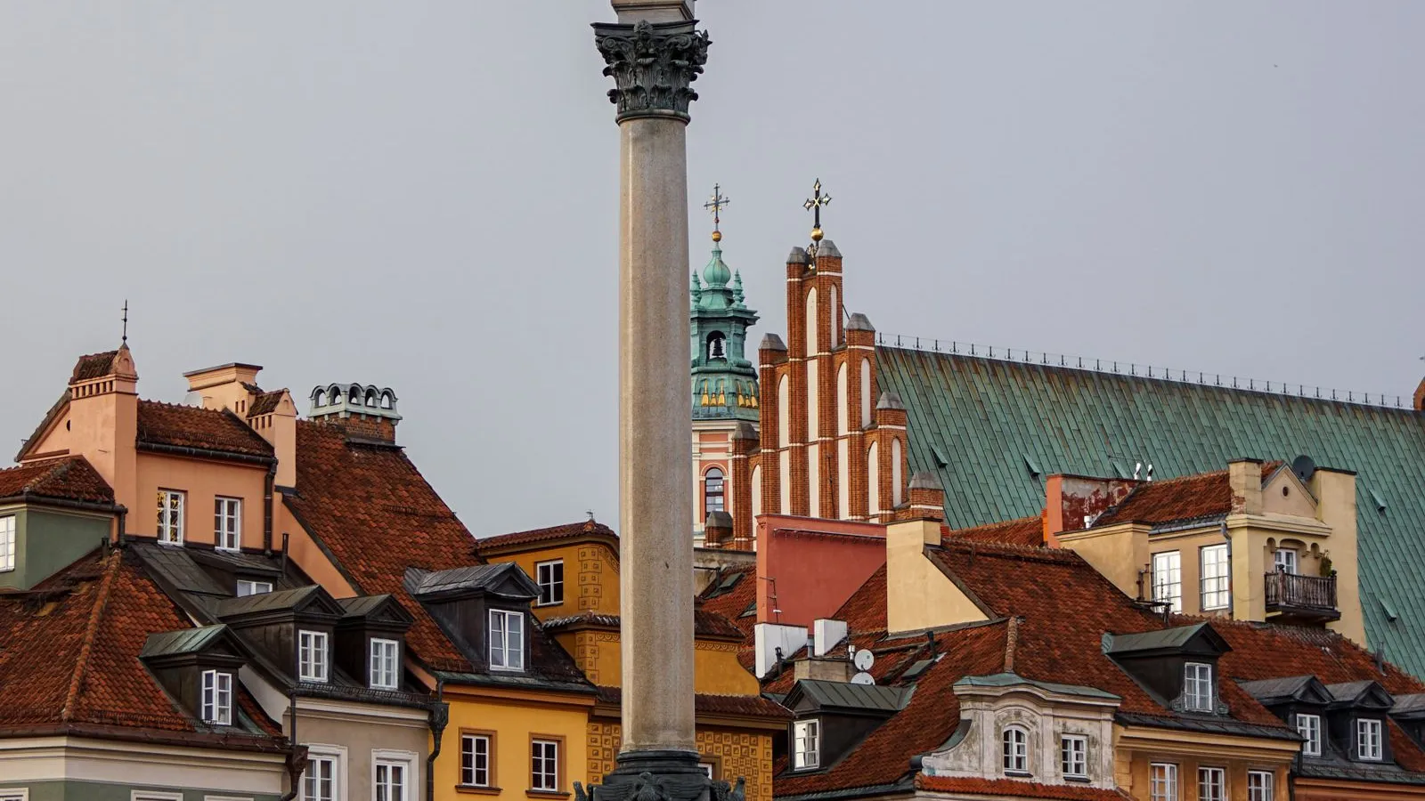 Sigismund's Column rising above the colourful townhouses and church towers of Castle Square in Warsaw's Old Town on a grey day